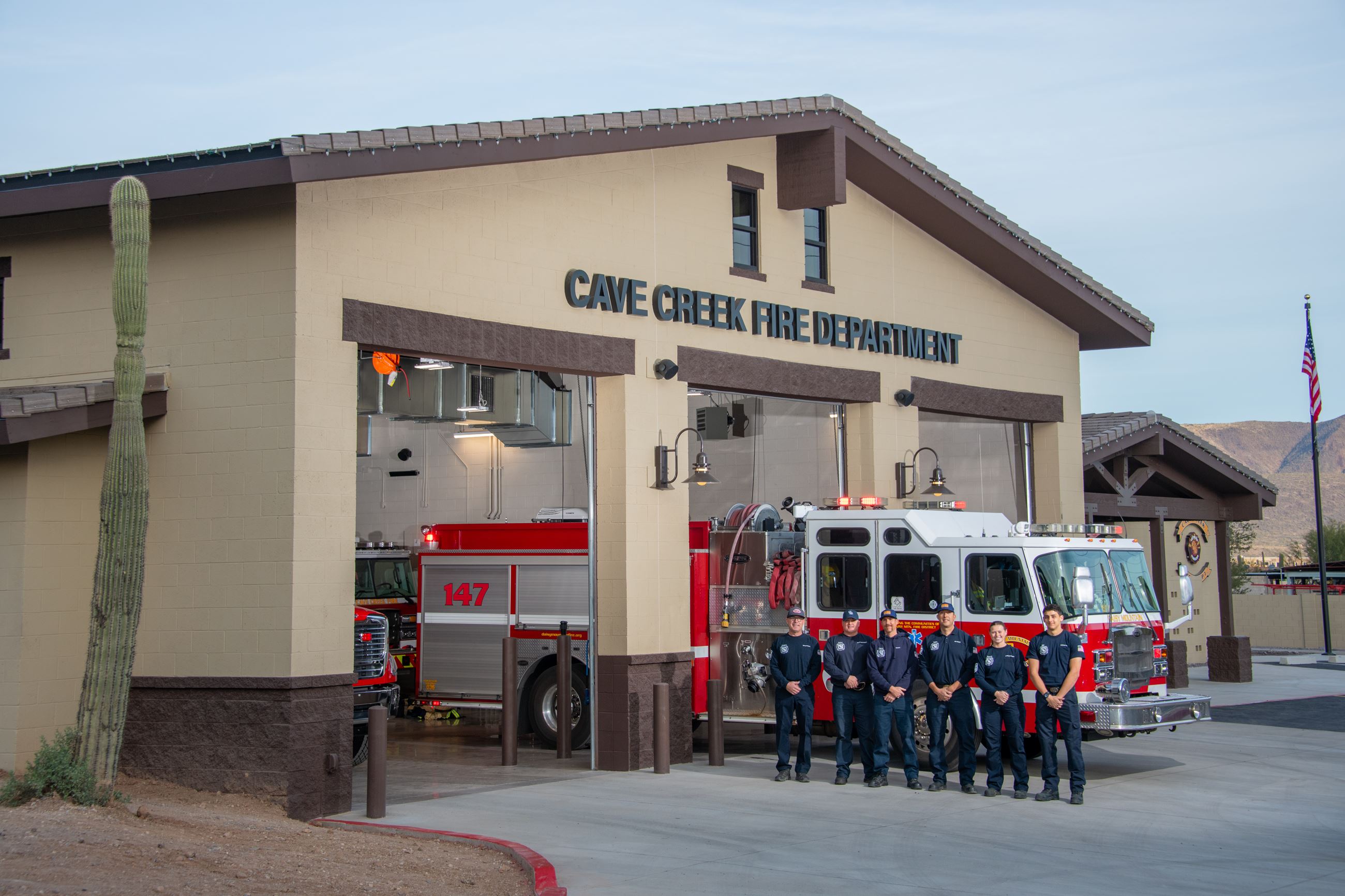 firefighters in front of station with fire truck